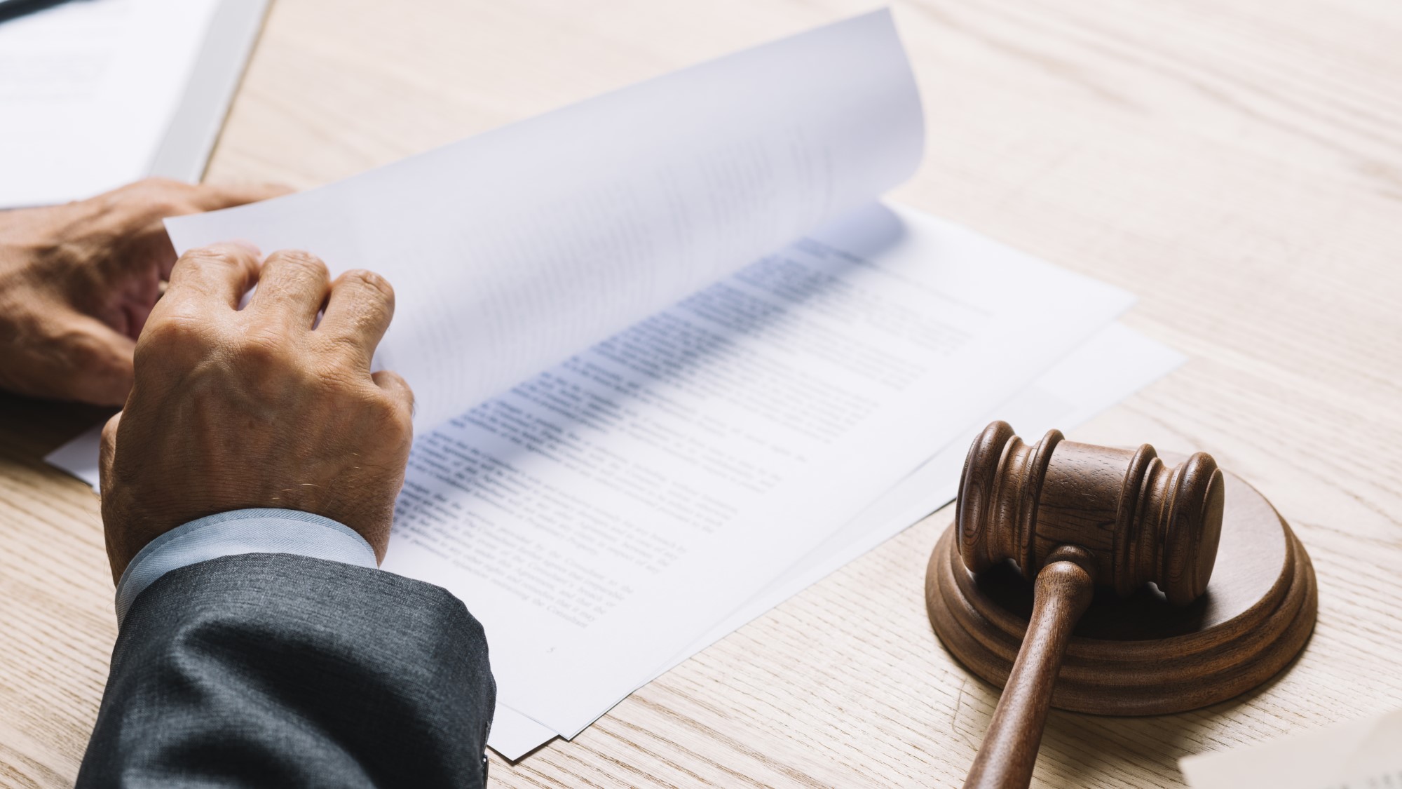 עורך דין מול שולחן עם מסמכים ופטיש בית משפט בצבע חום